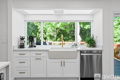 A kitchen with white cabinets and a window overlooking a green area.