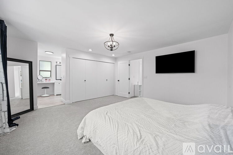 A bedroom with a large bed and a flat screen TV mounted on the wall.