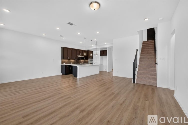 A spacious room with wooden flooring and a staircase leading to another level.