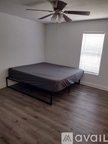 A bedroom with a bed, a ceiling fan, and a window with blinds.