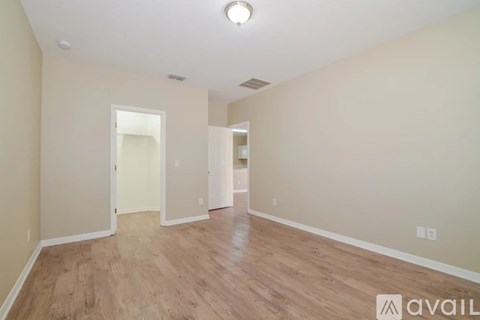 A spacious room with wooden flooring and two doors.