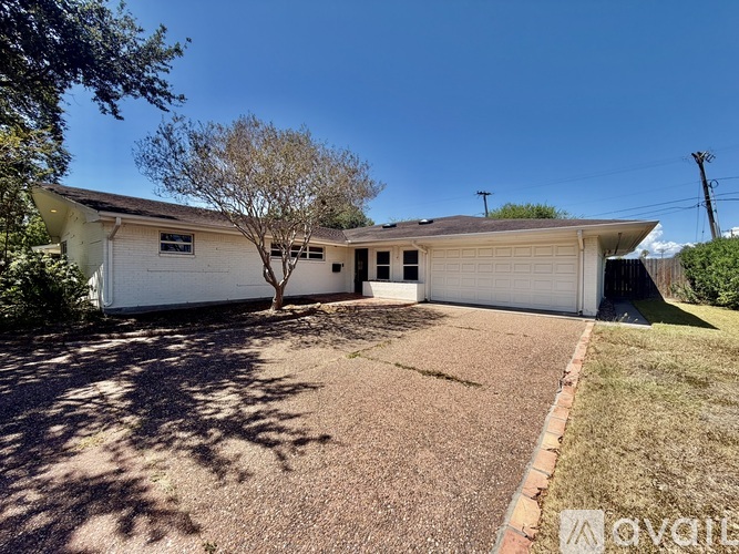 A house with a white garage door and a tree in front.