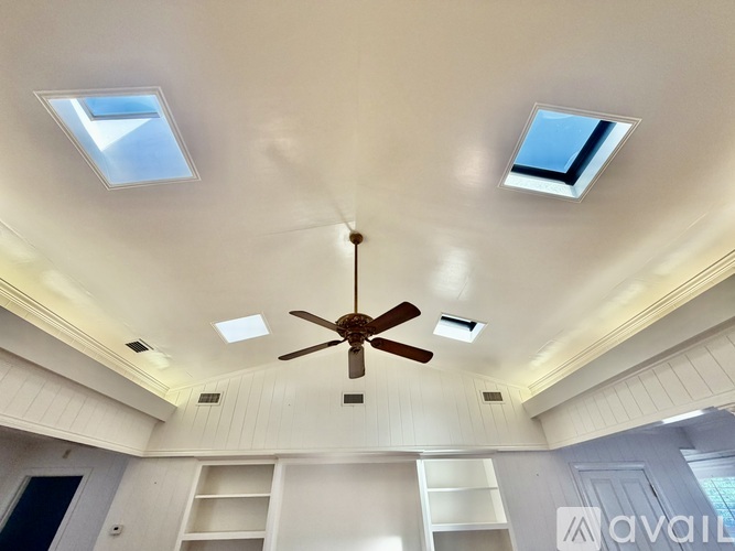 A room with a ceiling fan and skylights.