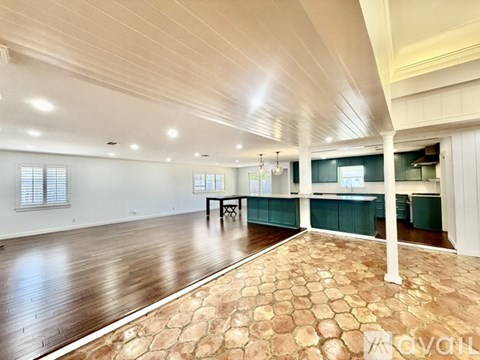 A spacious room with wooden flooring and a dining area with a table and chairs.