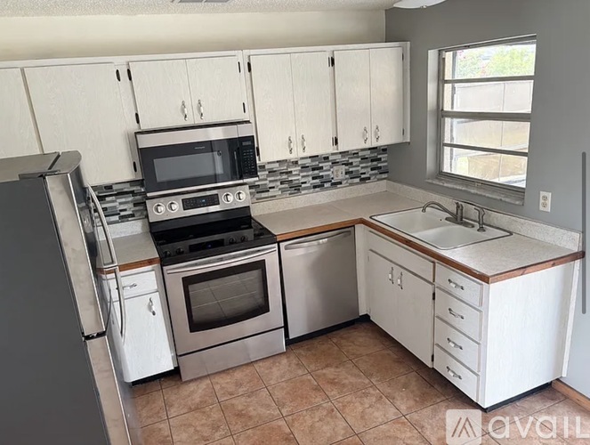 A kitchen with white cabinets and a tiled backsplash.