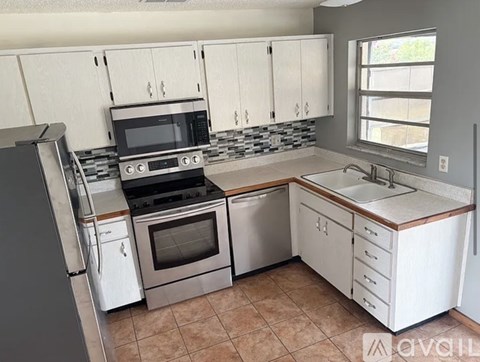 A kitchen with white cabinets and a tiled backsplash.