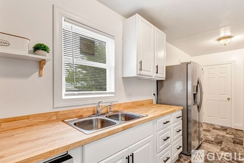A kitchen with white cabinets and a wooden countertop.