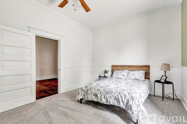 A bedroom with a bed, a lamp, and a ceiling fan.