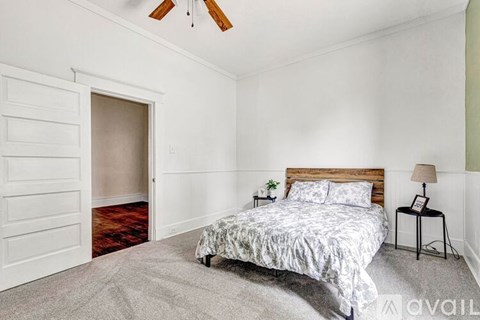 A bedroom with a bed, a lamp, and a ceiling fan.