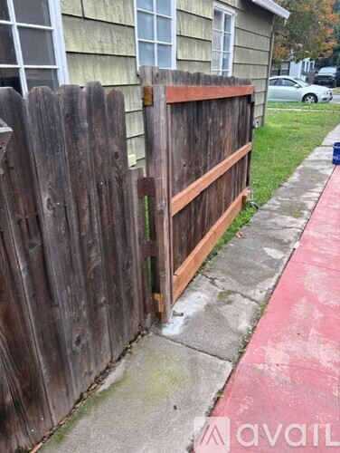 A wooden fence with a red stripe on the sidewalk.