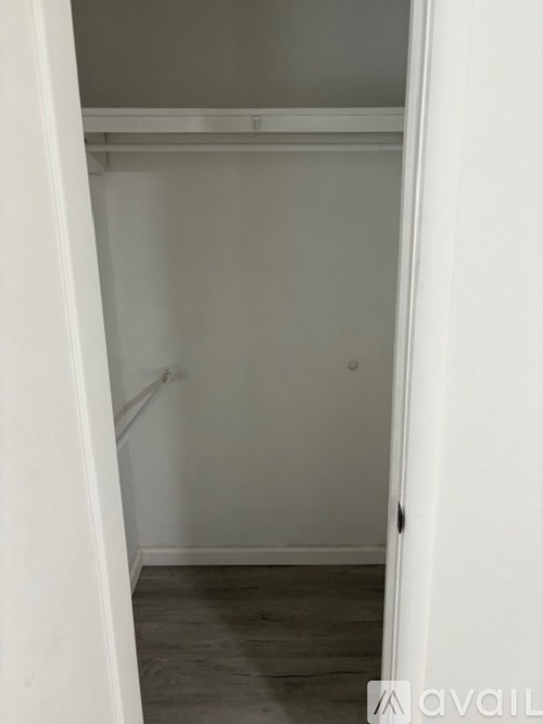 A white closet with a grey floor and a white door.