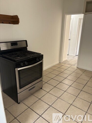 A kitchen with a black stove top oven and tiled floor.