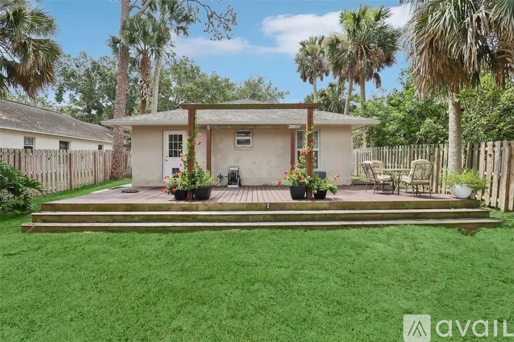 A house with a porch surrounded by a fence and trees.