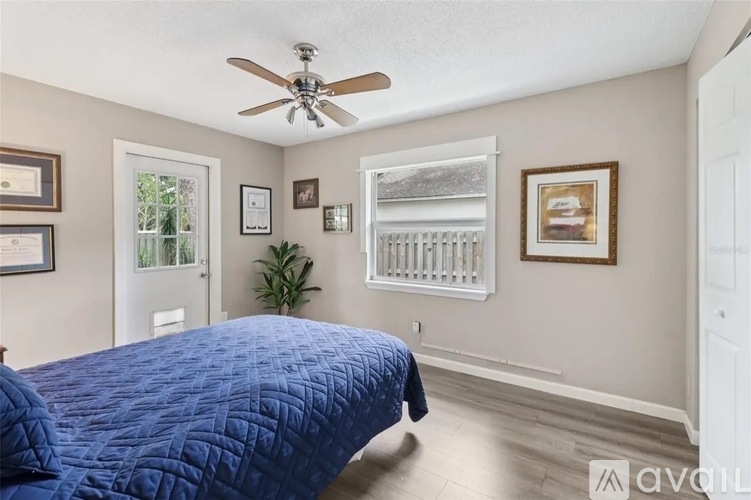 A bedroom with a blue bedspread and a ceiling fan.