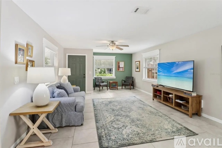 A living room with a grey couch, a wooden coffee table, a flat screen TV and a ceiling fan.