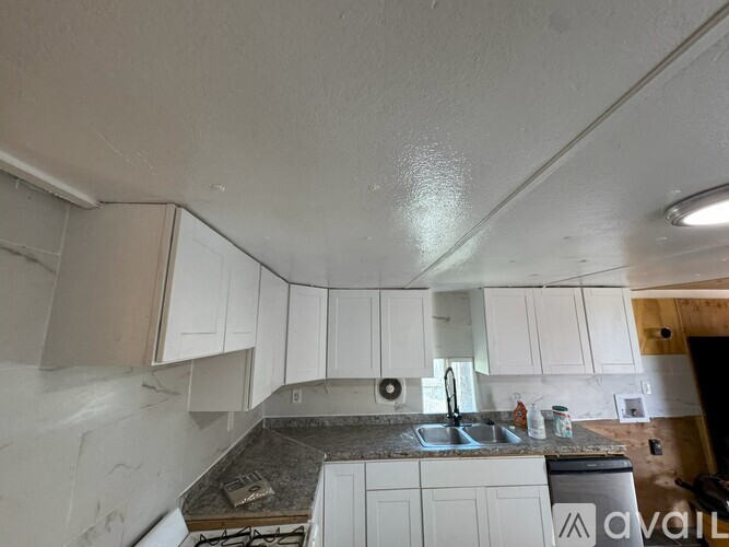 A kitchen with white cabinets and a granite countertop.