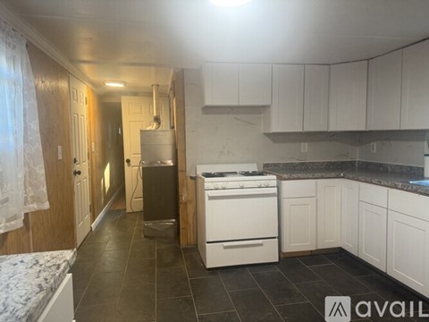 A kitchen with white cabinets and a black countertop.