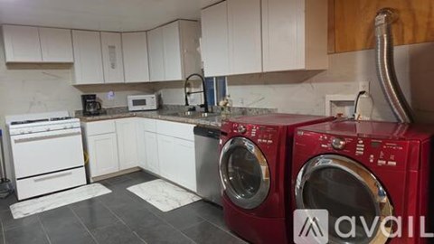 A kitchen with white cabinets and a red washing machine.