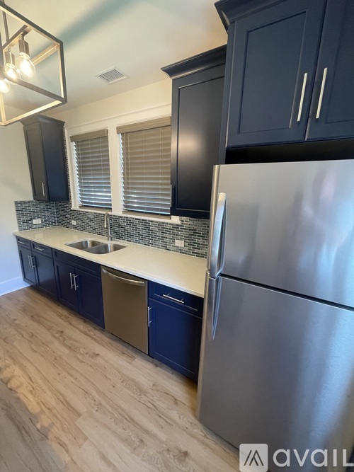 A kitchen with a stainless steel refrigerator and wooden flooring.