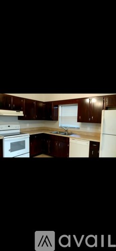 A kitchen with dark brown cabinets and white appliances.