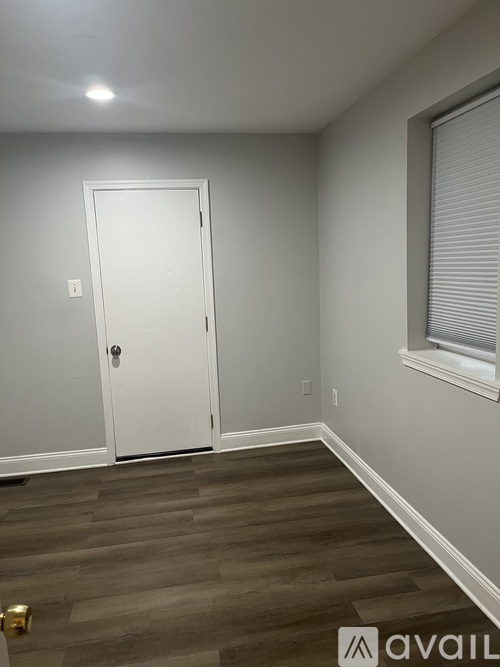 A room with a white door and a window with blinds.