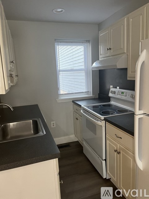 A kitchen with white cabinets and a black countertop.