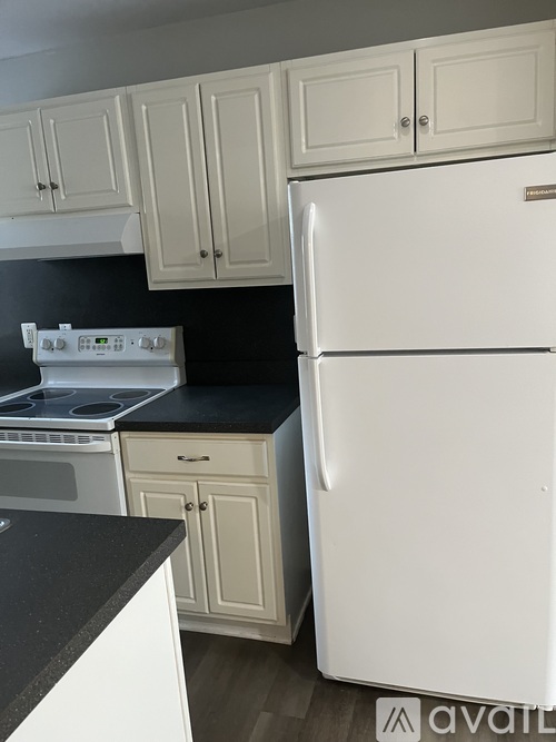A white refrigerator is in a kitchen with white cabinets.