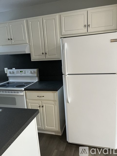 A white refrigerator is in a kitchen with white cabinets.