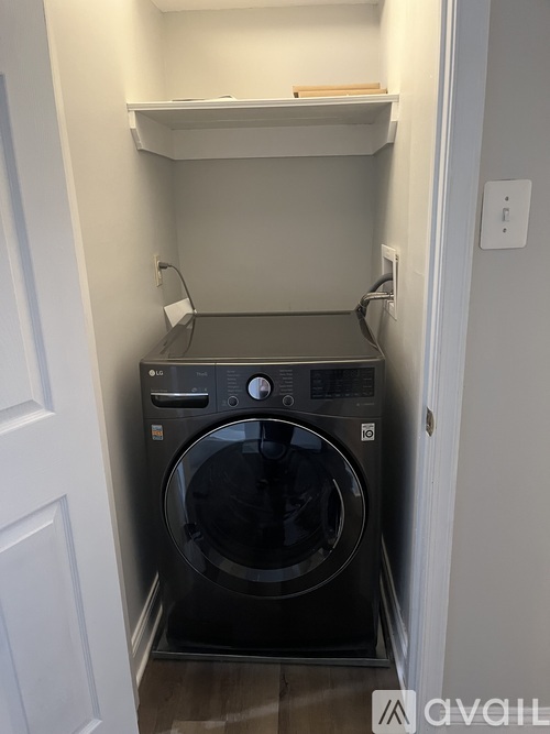A black washing machine in a small laundry room.