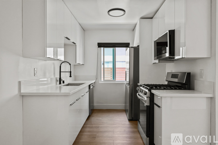 A modern kitchen with white cabinets and a black stove top oven.