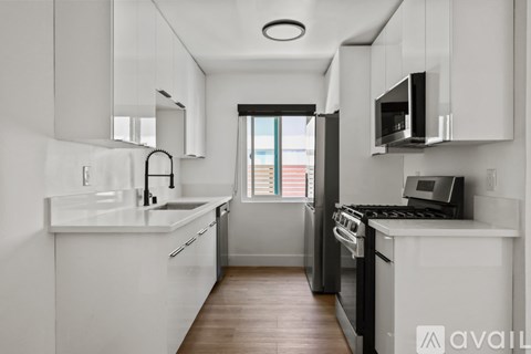A modern kitchen with white cabinets and a black stove top oven.