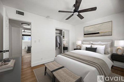 A bedroom with a large bed and a ceiling fan.