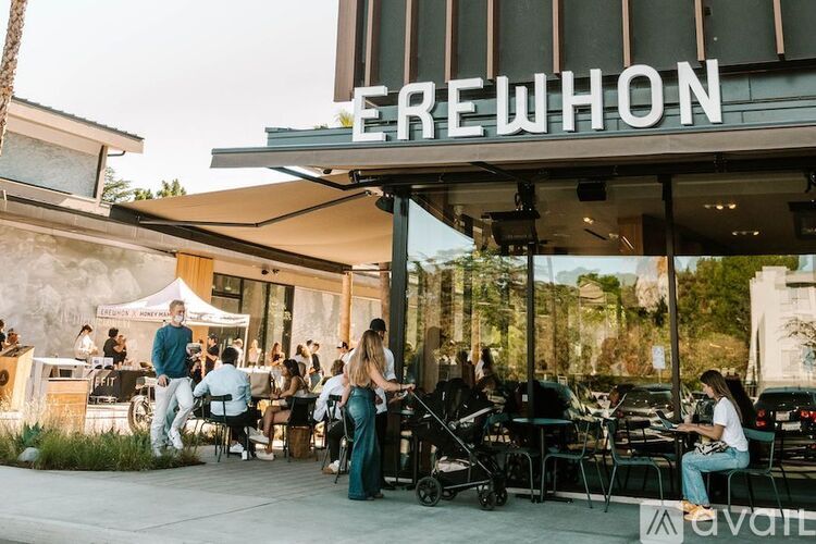 A group of people are sitting outside a building with a sign that reads "FREWHON".