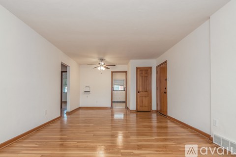 A spacious room with wooden floors and a ceiling fan.