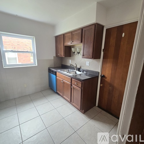 A kitchen with brown cabinets and a blue trash can.
