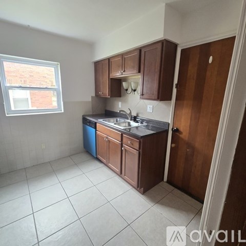 A kitchen with brown cabinets and a blue trash can.
