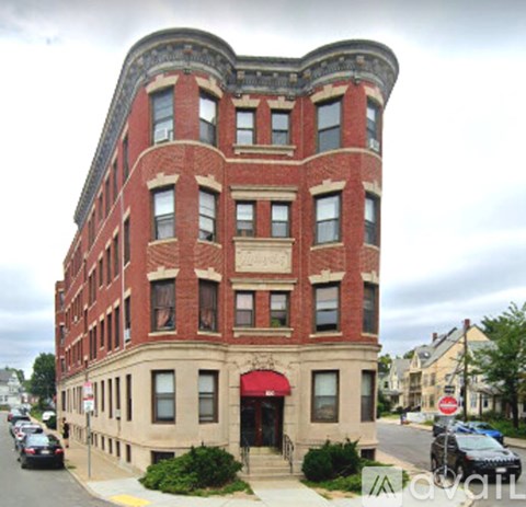 A red brick building with a red awning sits on a street corner.