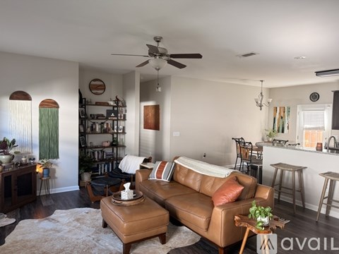 A living room with a brown leather couch and a ceiling fan.