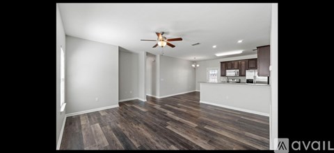 A spacious room with wood flooring and a ceiling fan.