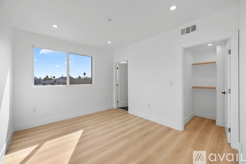 A spacious room with wooden flooring and a large window overlooking a desert landscape.