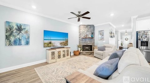 A living room with a white couch and a painting of a beach scene on the wall.