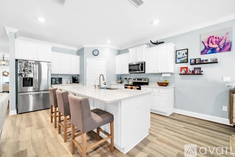 A kitchen with white cabinets and a white island with a counter top.
