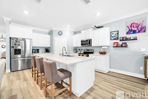A kitchen with white cabinets and a white island with a counter top.