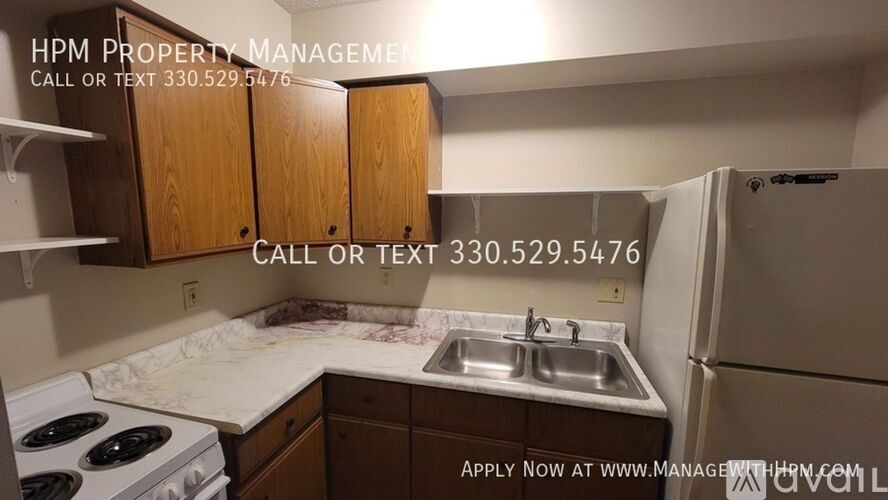 A kitchen with a stove, sink, and cabinets with a sign for HPM Property Management.