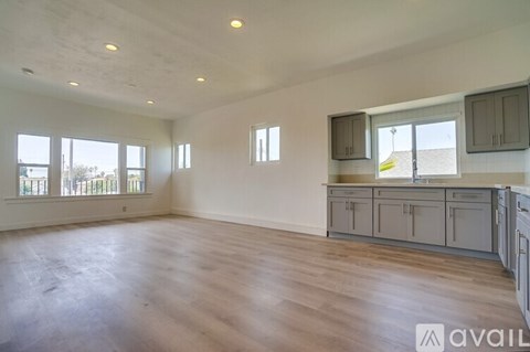 A spacious empty room with wooden floors and a large window.