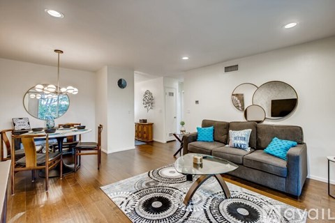 A living room with a grey couch and a glass table.