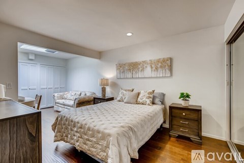 A bedroom with a large bed and a painting on the wall.