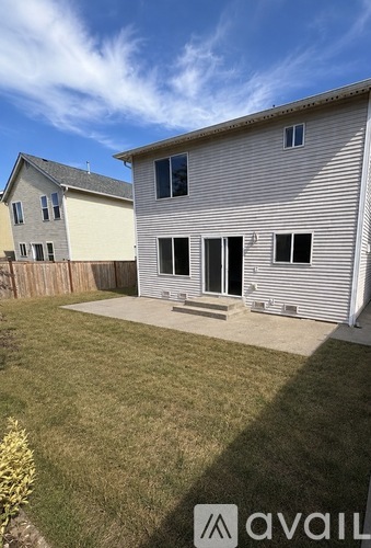 A house with a white exterior and a grey roof is shown with a clear blue sky in the background.