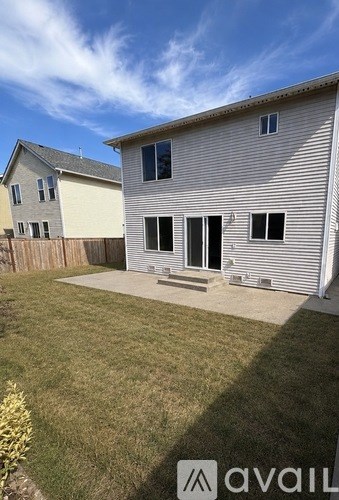 A house with a white exterior and a grey roof is shown with a clear blue sky in the background.