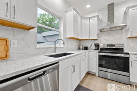A kitchen with white cabinets and a marble countertop.